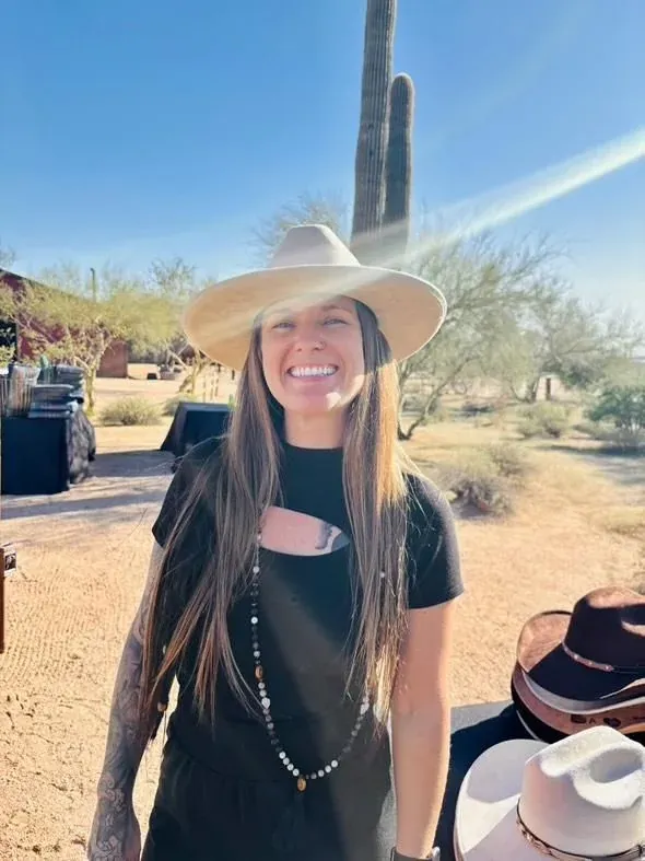 Tiffany Lehman smiling outdoors in the Arizona desert wearing a wide-brim hat