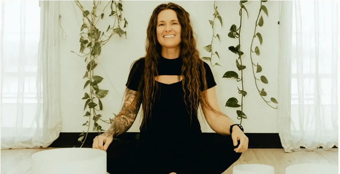 Tiffany Lehman seated among singing bowls in a bright studio