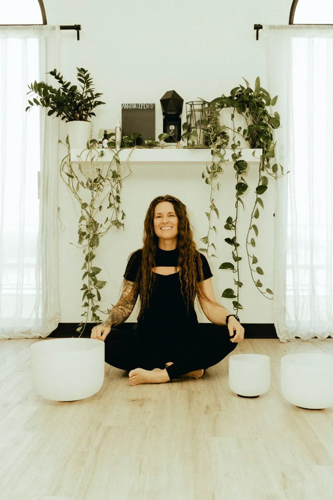 Tiffany Lehman seated in meditation between crystal singing bowls