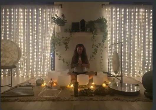 A candlelit sound bath setting with crystal bowls, gongs, and chimes